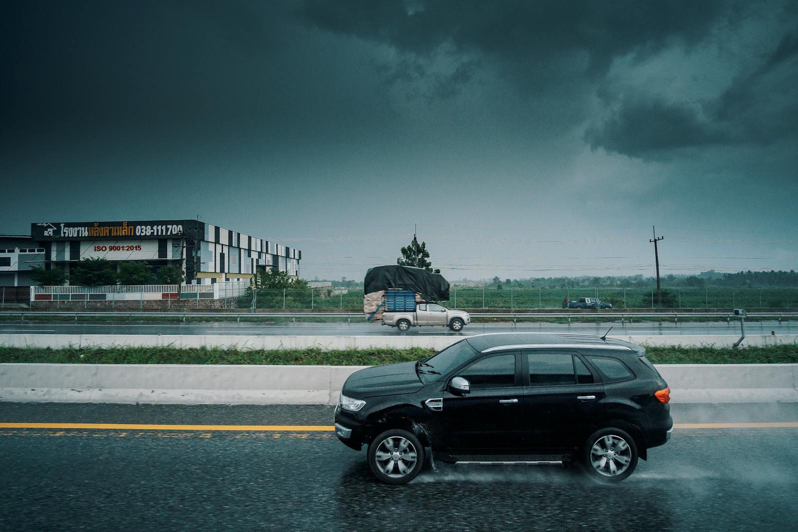 Driving Safety Tips Black SUV travels on a rainy highway, showcasing stormy weather and transportation dynamics.